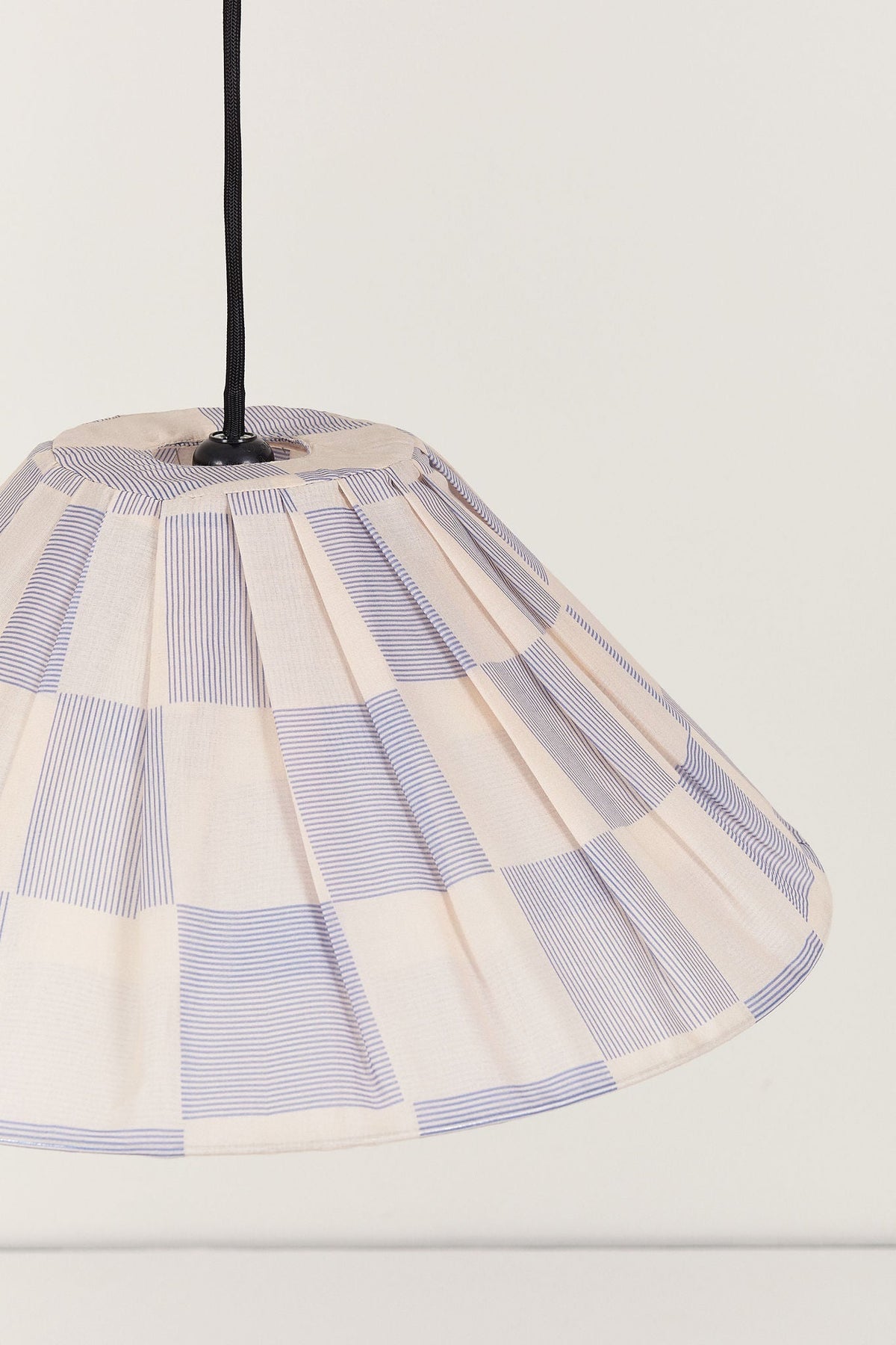 Nobodinoz Ava geplooide lampenkap van 50 cm in inktblauw ruit in een licht, mediterraan ingericht interieur.