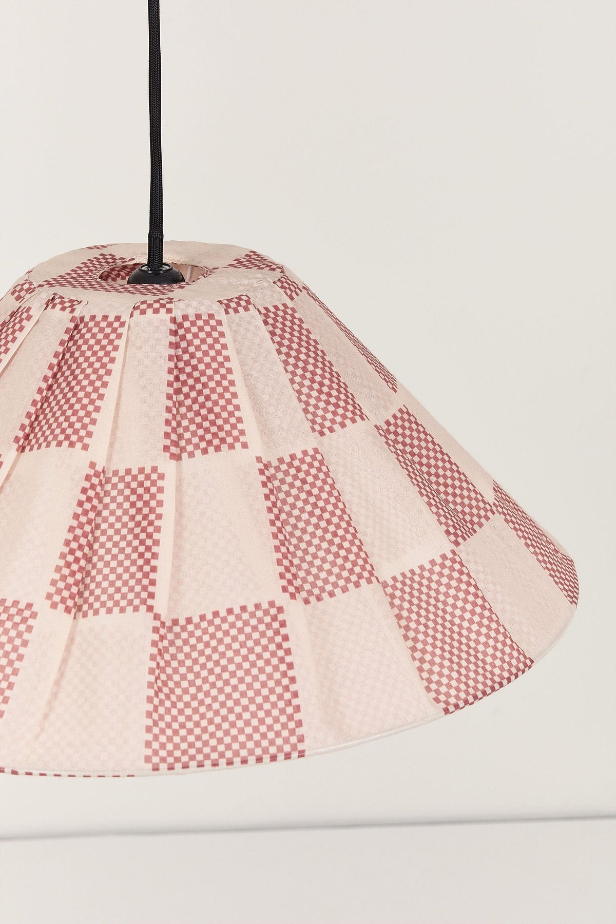 Nobodinoz Ava geplooide lampenkap van 50 cm in gebrand rood ruit in een licht, mediterraan ingericht interieur.