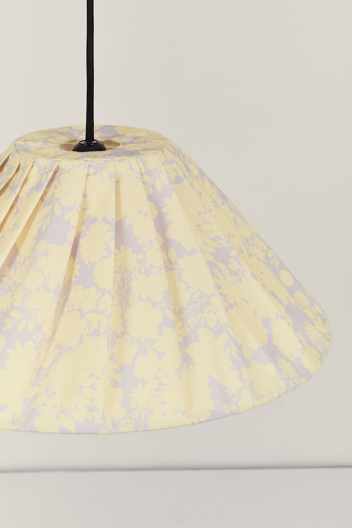 Nobodinoz Ava geplooide lampenkap van 50 cm in gele bloemen in een licht, mediterraan ingericht interieur.