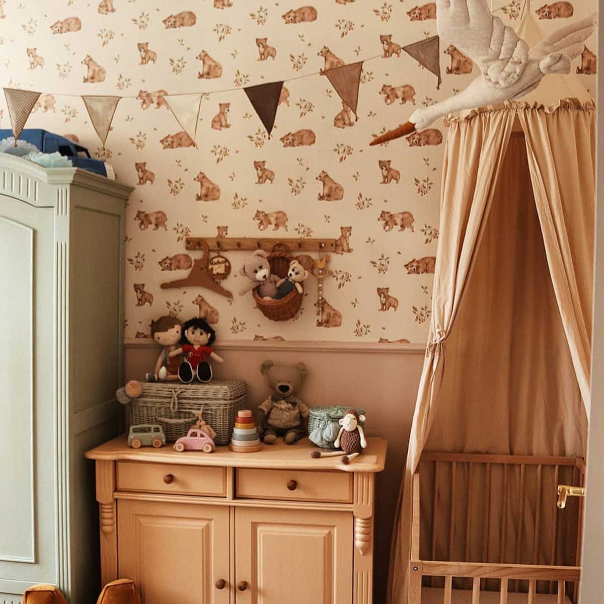 Dekornik Little Lambs Behang — Een lief behang met kleine lammetjes tussen bloemen en gras, in zachte pasteltinten, perfect voor een dromerige babykamer. Sfeerbeeld van het behang in een ingerichte kinderkamer.